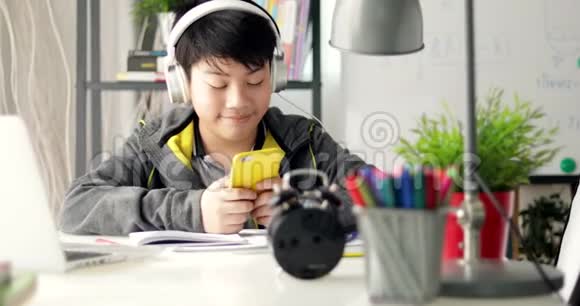 年轻的十几岁的学生听智能手机的音乐在家做家庭作业多莉右向左移动视频的预览图
