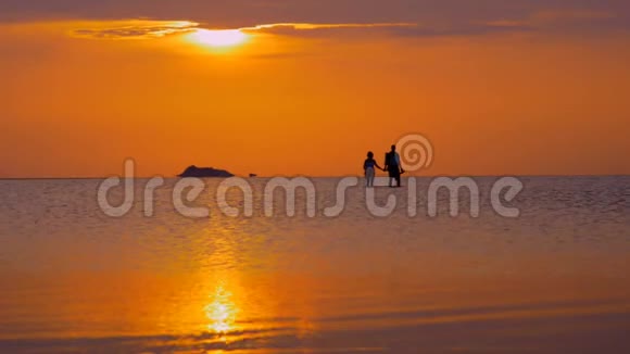 日落时分在海里散步的情侣视频的预览图