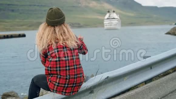 年轻女子坐在港口看游轮离开视频的预览图