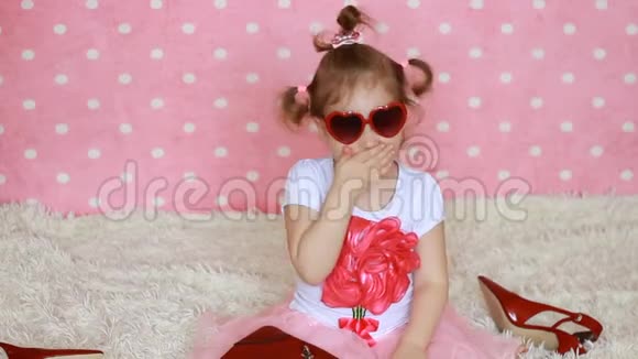 可爱的小女孩戴着红色太阳镜心形送空气吻粉色背景时尚界人士视频的预览图