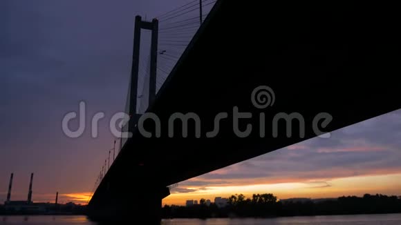 日落时分在高高的大桥下观赏河上的灯笼连接两岸的建筑建筑视频的预览图