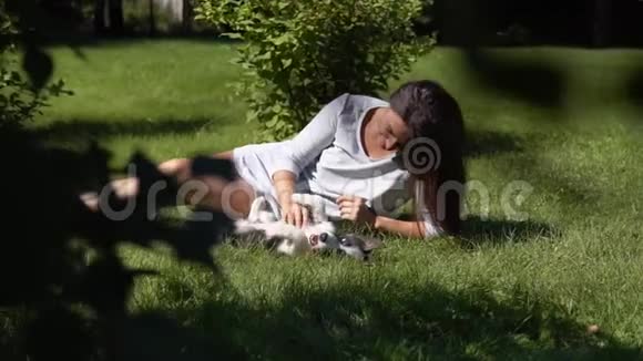 有长发的小女孩在草地上的公园里和一只小狗玩慢动作视频的预览图