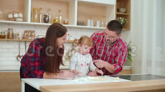 快乐的年轻人和蹒跚学步的女孩在厨房里玩面粉视频的预览图