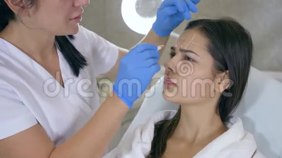 美容师在美容院用白铅笔在女孩脸上标出问题部位视频的预览图