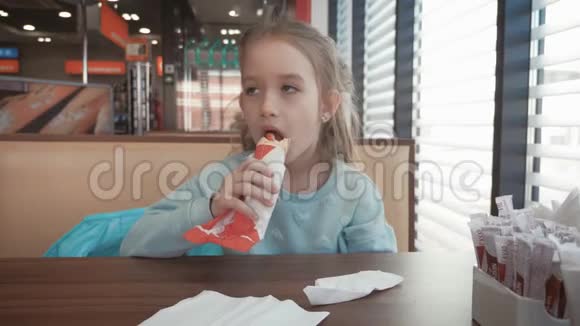 漂亮的女孩在路边的咖啡馆里吃热狗快餐在汽车旅行的概念视频的预览图