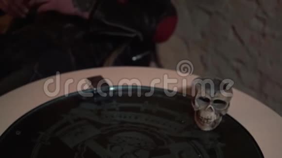 男人手拿着威士忌酒杯放在打火机和头骨旁边视频的预览图