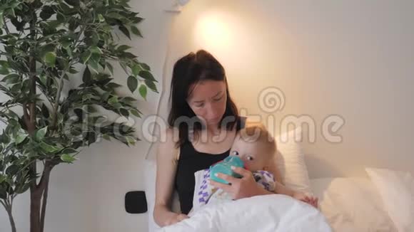年轻的母亲在家里用一瓶牛奶喂她的小儿子视频的预览图