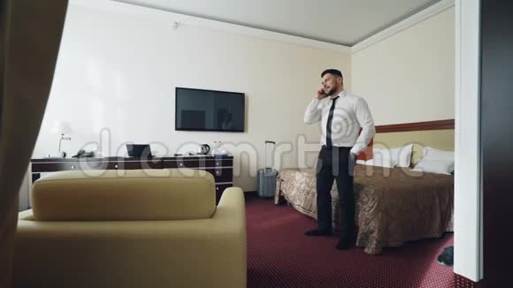 自信的商人在酒店房间里走来走去用手机说话旅游商业和人的概念视频的预览图