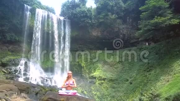 Flycam展示了泡沫状的瀑布流和岩石上的女孩视频的预览图