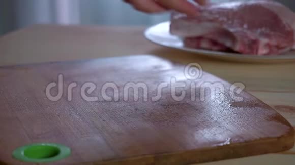 家庭主妇把新鲜的猪肉牛排放在桌子上把盐洒在上面慢节奏视频的预览图