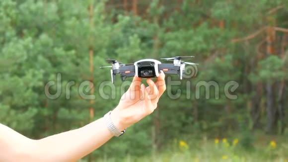 一个人绿色森林的背景下手握一架无人机或四架直升机未来技术视频的预览图