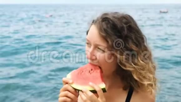一个女人在大海的背景下咬掉西瓜的肖像视频的预览图
