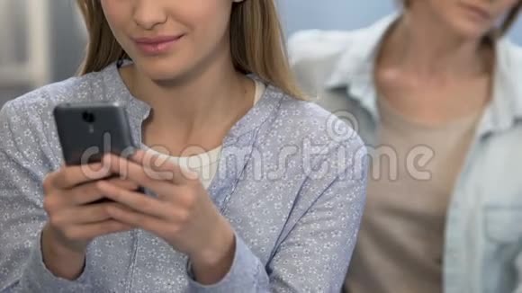 十几岁的女儿在智能手机上玩电子游戏无视母亲特写视频的预览图