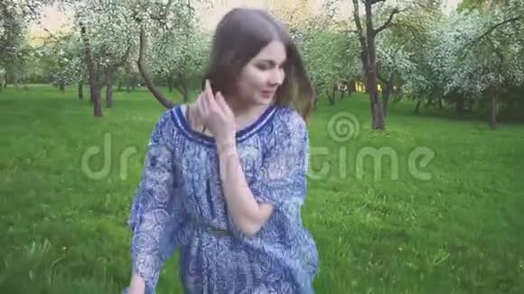 年轻的女人跑在一个苹果园里的春天花白色傍晚水果中一个美丽女孩的肖像视频的预览图