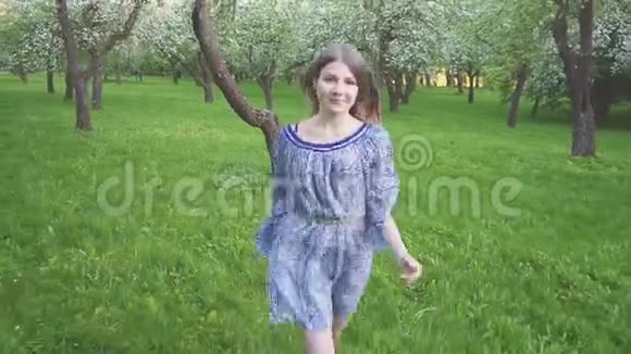 诱惑的年轻女子跑在一个苹果园的春天花白晚上一个漂亮女孩的肖像视频的预览图