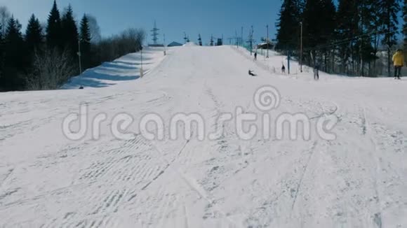 12岁的小男孩穿着灰色西装从下一天的雪下滑到滑雪板上从远处看视频的预览图