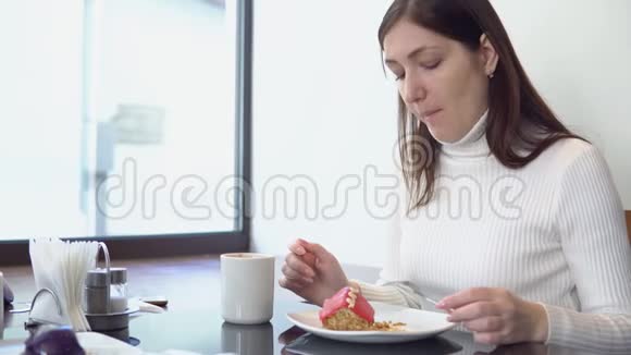 美丽的女人在咖啡馆的桌子上吃蛋糕喝咖啡视频的预览图
