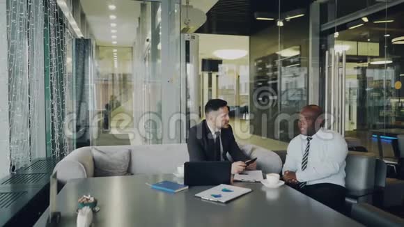 两位穿着正式服装的乐观男性企业家在咖啡馆讨论他们的创业项目非裔美国人和视频的预览图