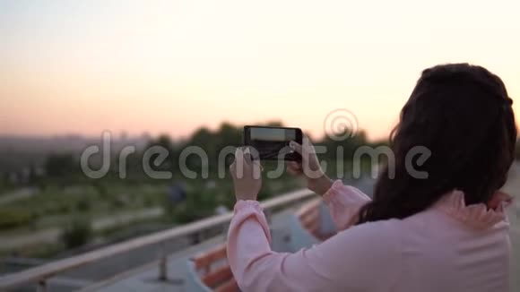 一个女孩用智能手机拍了一张城市的照片慢动作视频的预览图