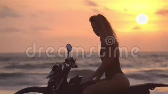 一个女孩骑着自行车在一个红色坐着的太阳的背景下抱着她的手臂在油箱上的美妙景色视频的预览图