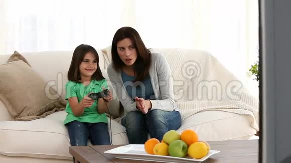 快乐的妈妈鼓励女儿玩电子游戏视频的预览图