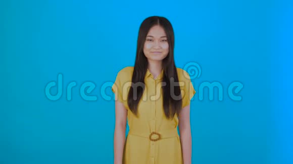 漂亮的亚洲女人微笑着与蓝色背景隔绝视频的预览图