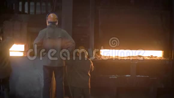 冶金生产现场在阴沉的商店里工人们监视着炉子的运行在炉子下面视频的预览图
