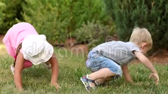 两个有趣的孩子在公园里躺在草地上玩视频的预览图