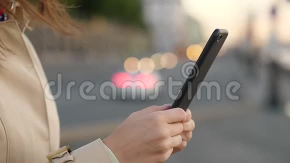 女士双手使用智能手机靠近晚道和汽车前灯视频的预览图