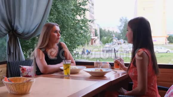 两个长发女孩正在一家咖啡馆里休息里面有一个现代的内部和笑声室内滑稽微笑女士画像视频的预览图