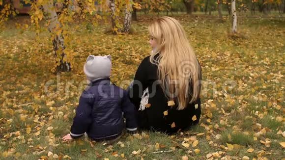 妈妈和男孩在秋天公园摔倒在地视频的预览图