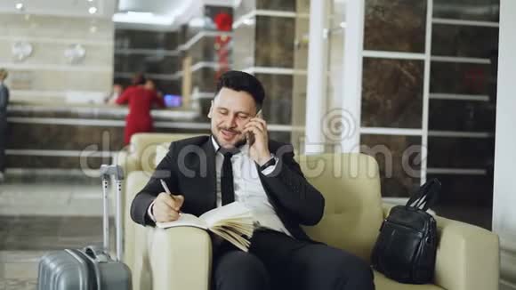 潘在坐着的时候拍了一张欢快自信的商人在玩手机时微笑着写笔记视频的预览图