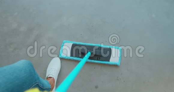 在打扫房子的地板时戴着防护手套的漂亮年轻女人用一个扁平的湿拖把遮住的形象视频的预览图