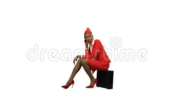 穿着红色西装的非裔美国空姐坐在手提箱上打哈欠阿尔法通道视频的预览图