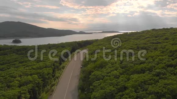 空中射击无人驾驶飞机在公路和森林上空移动附近有大海视频的预览图