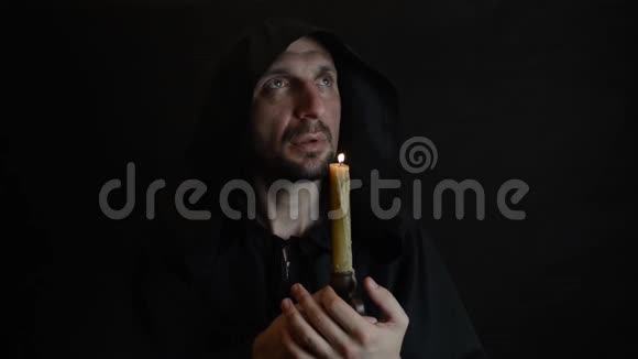 一个留胡子的和尚在烛光下祈祷蜡烛的火焰熄灭了视频的预览图