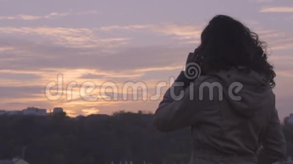 年轻自信的女人在日落时分完成手机对话自由视频的预览图