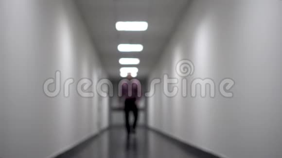 一个人沿着长长的白色走廊走去背景模糊视频包含闪烁和噪音视频的预览图