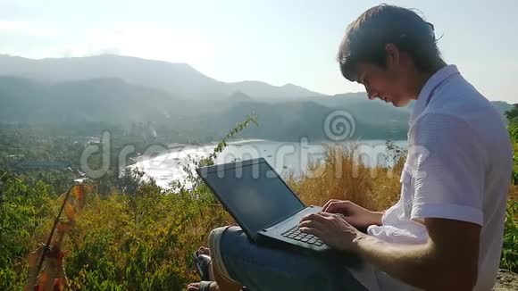 商人坐在岩石上用笔记本电脑工作慢动作1920x1080视频的预览图