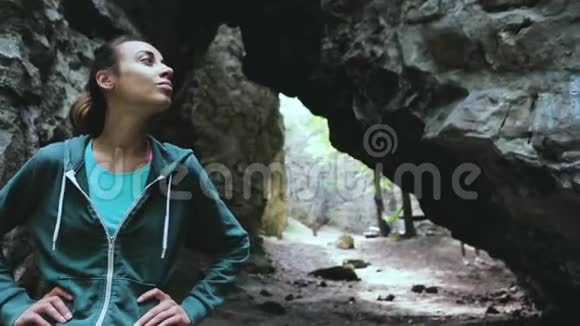 一位女游客高兴地看着森林里的岩石视频的预览图