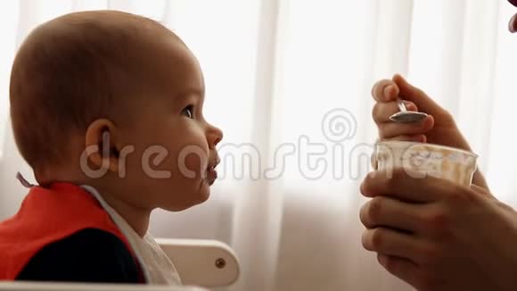 一个年轻快乐的父亲慢吞吞地喂他的儿子婴儿粥视频的预览图