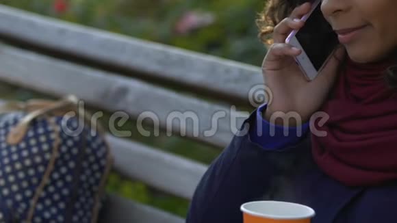 多种族妇女拿着热茶在户外打电话交谈视频的预览图