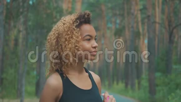 黑色女人从粉红色的瓶子里喝黑人年轻女子慢跑休息的肖像视频的预览图