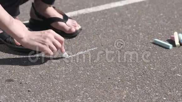 女人用白色粉笔在沥青上画一个正方形特写双手视频的预览图