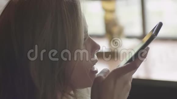 女人用电话发送音频信息坐在咖啡馆里视频的预览图