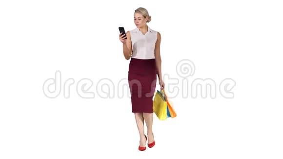美丽迷人的女人看着智能手机拿着购物袋走在白色的背景上视频的预览图