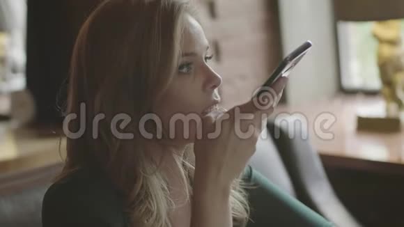 女人用电话发送音频信息坐在咖啡馆里视频的预览图