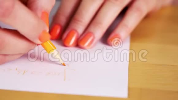 女人拿着一支橙色的铅笔在白纸上做笔记视频的预览图