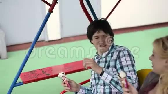 年轻可爱的一对荡秋千吃着冰奶油玩得开心视频的预览图