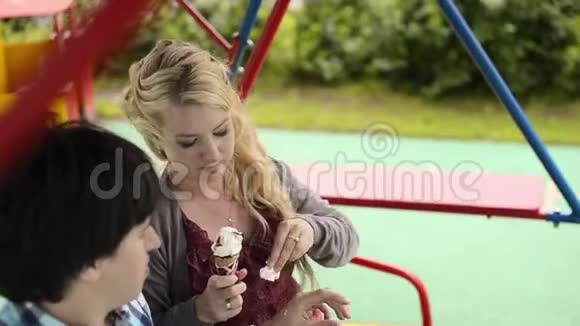 年轻可爱的一对荡秋千吃着冰奶油玩得开心视频的预览图